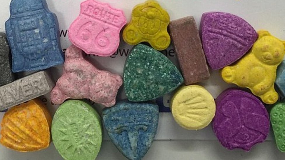 A hand holding MDPV powder with a UK and EU flag, symbolizing online purchase options